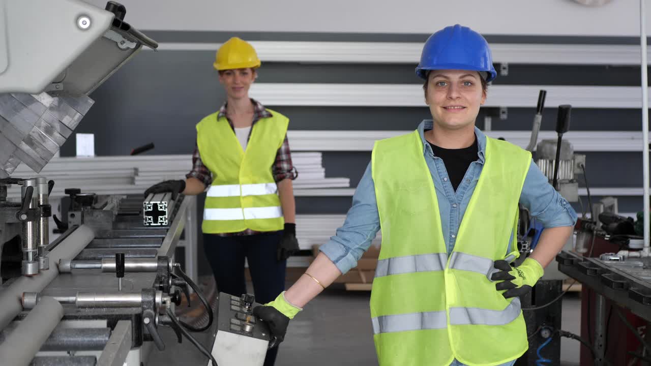 女工在工厂工作，穿着防护工作服和头盔，看着摄像机视频素材