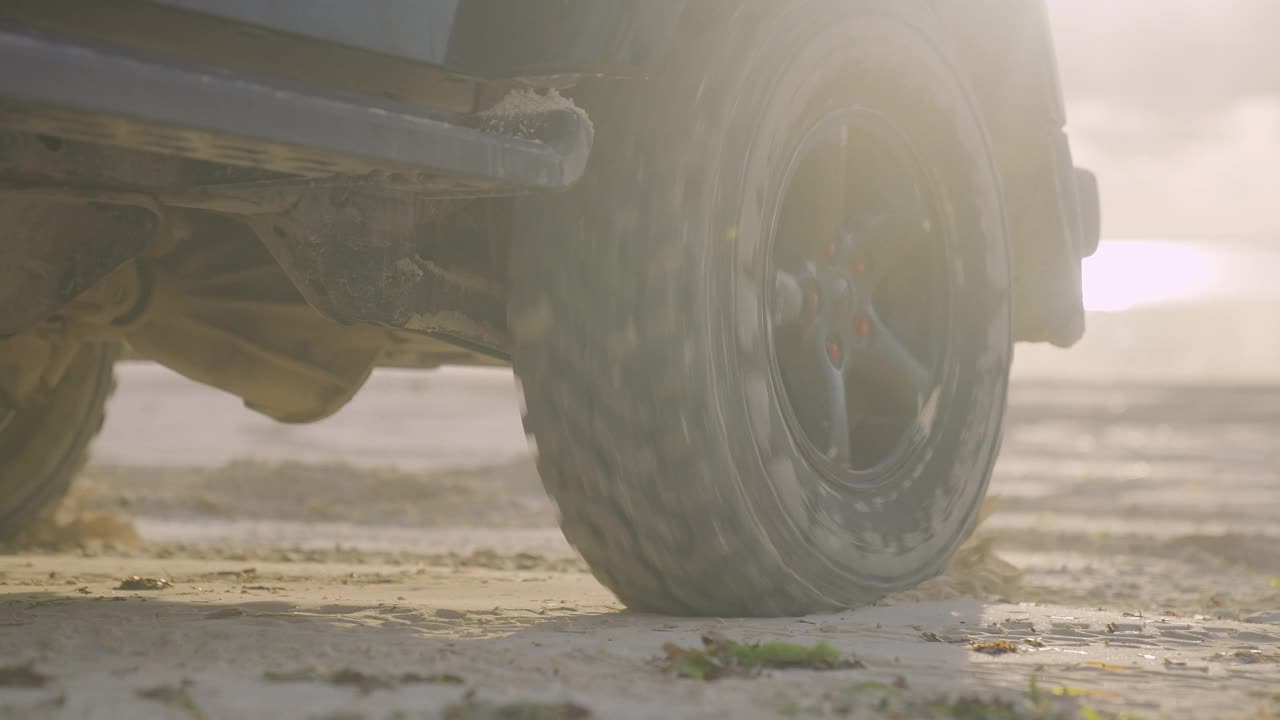 水和沙子从SUV车轮上溅起。海滩之旅，特写镜头视频下载