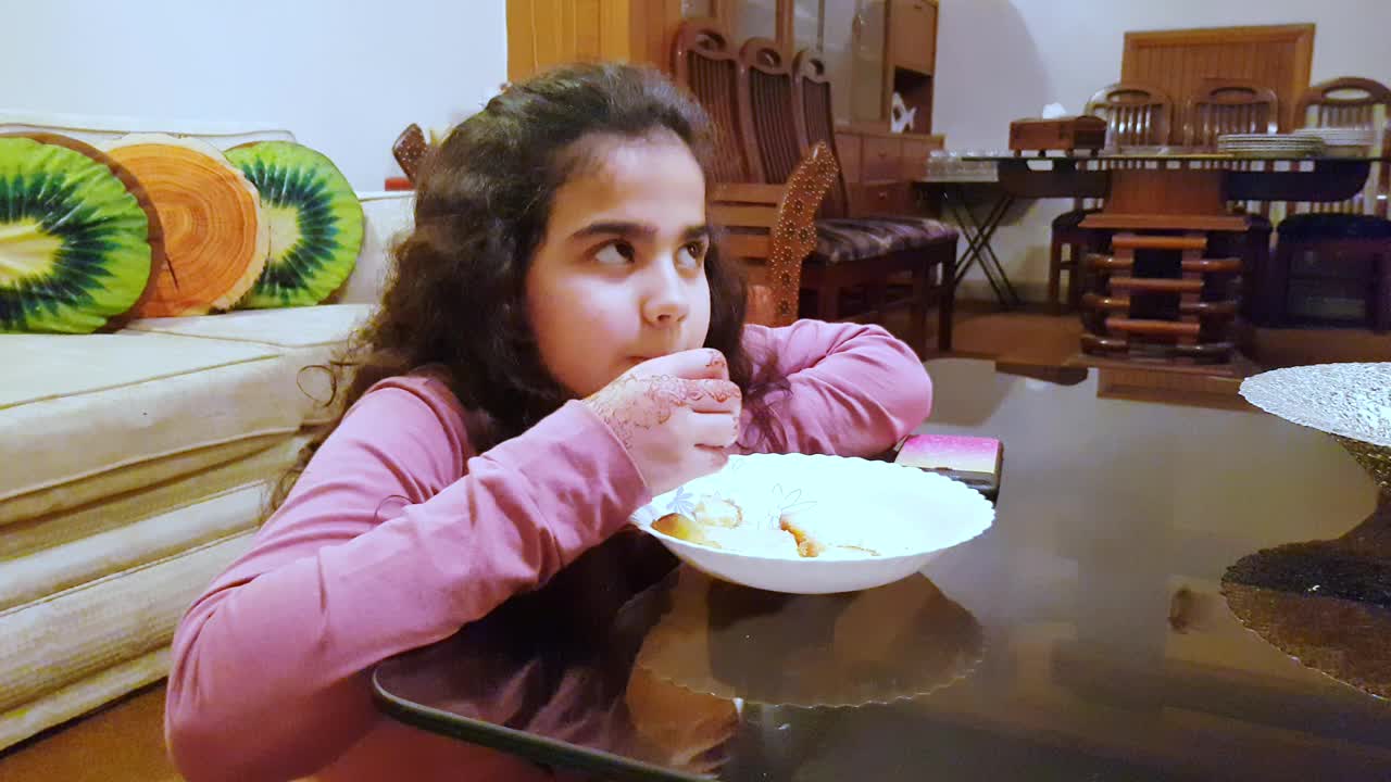 一个小女孩坐在地板上吃东西。视频下载