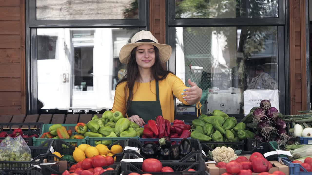 开朗的女蔬菜水果商在农贸市场提供本地产品视频素材