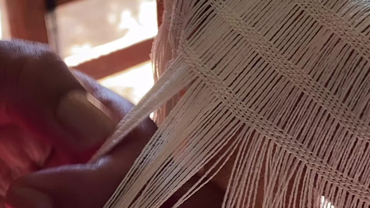 一名妇女正在手工编织的纺织品上打结流苏视频下载