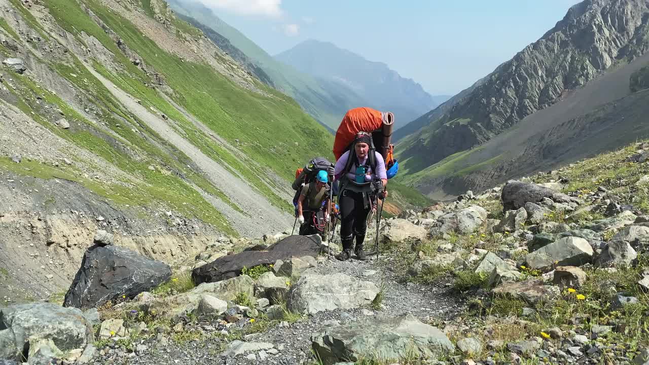 一个背着大背包的女人走在山路上视频素材