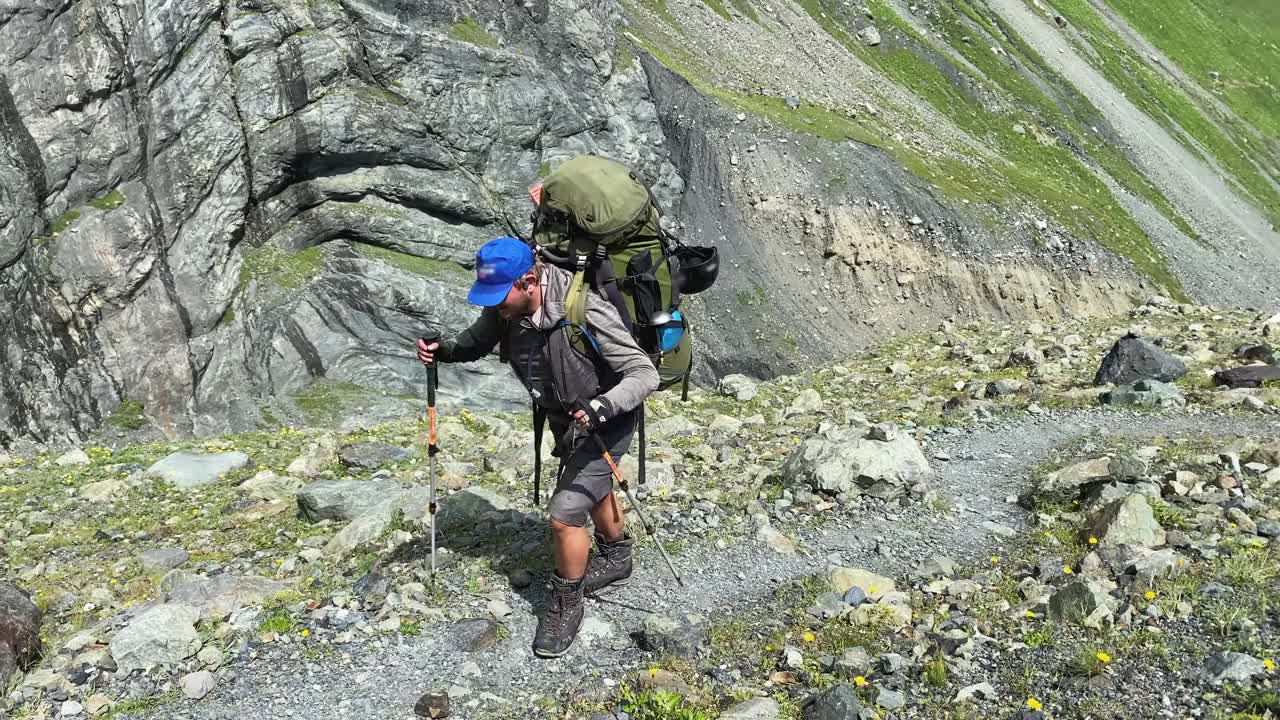 一个徒步旅行者背着一个大背包沿着山路走。从北部攀登卡兹别克视频下载