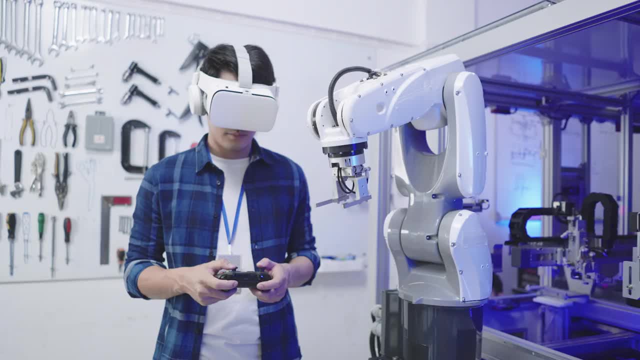 前视图:亚洲软件工程师青年男子通过无线控制器和虚拟仿真眼镜控制自动化机器人手臂生产线的运动系统视频下载
