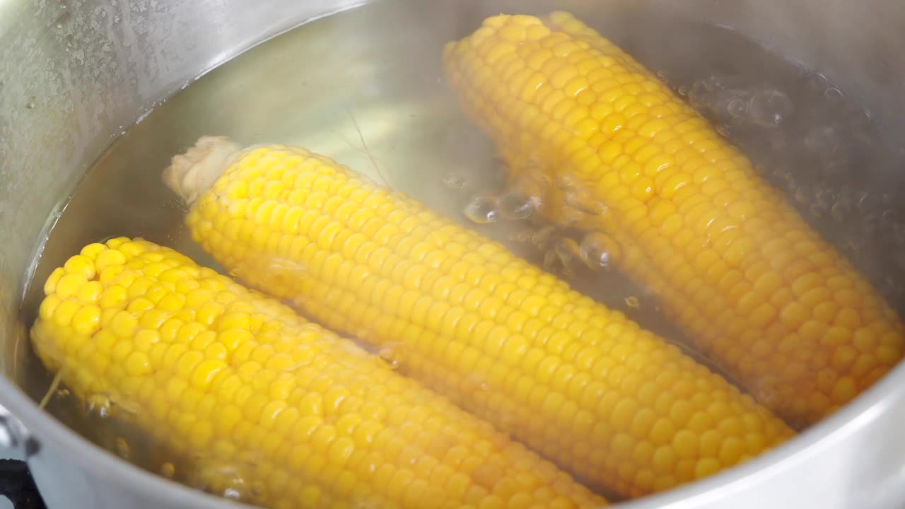 特写镜头:锅里的玉米在热水中沸腾。新鲜的黄色玉米棒放在沸水里。视频4 k的决议视频素材