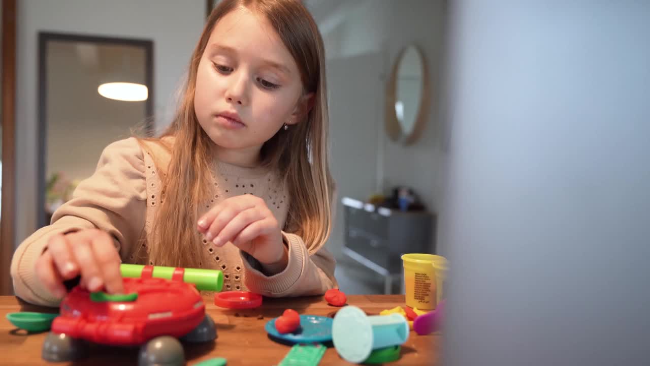 可爱的女孩在家里用橡皮泥装饰玩具视频下载