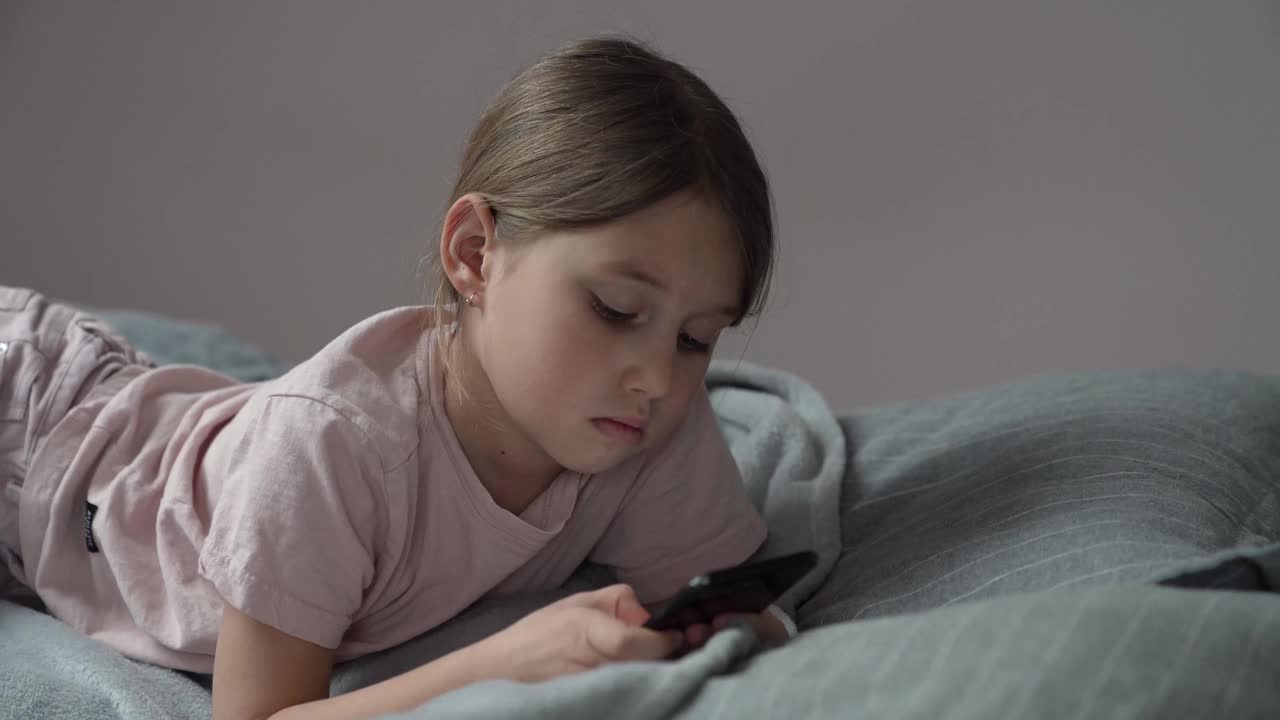 伤心的小女孩躺在床上玩手机视频下载