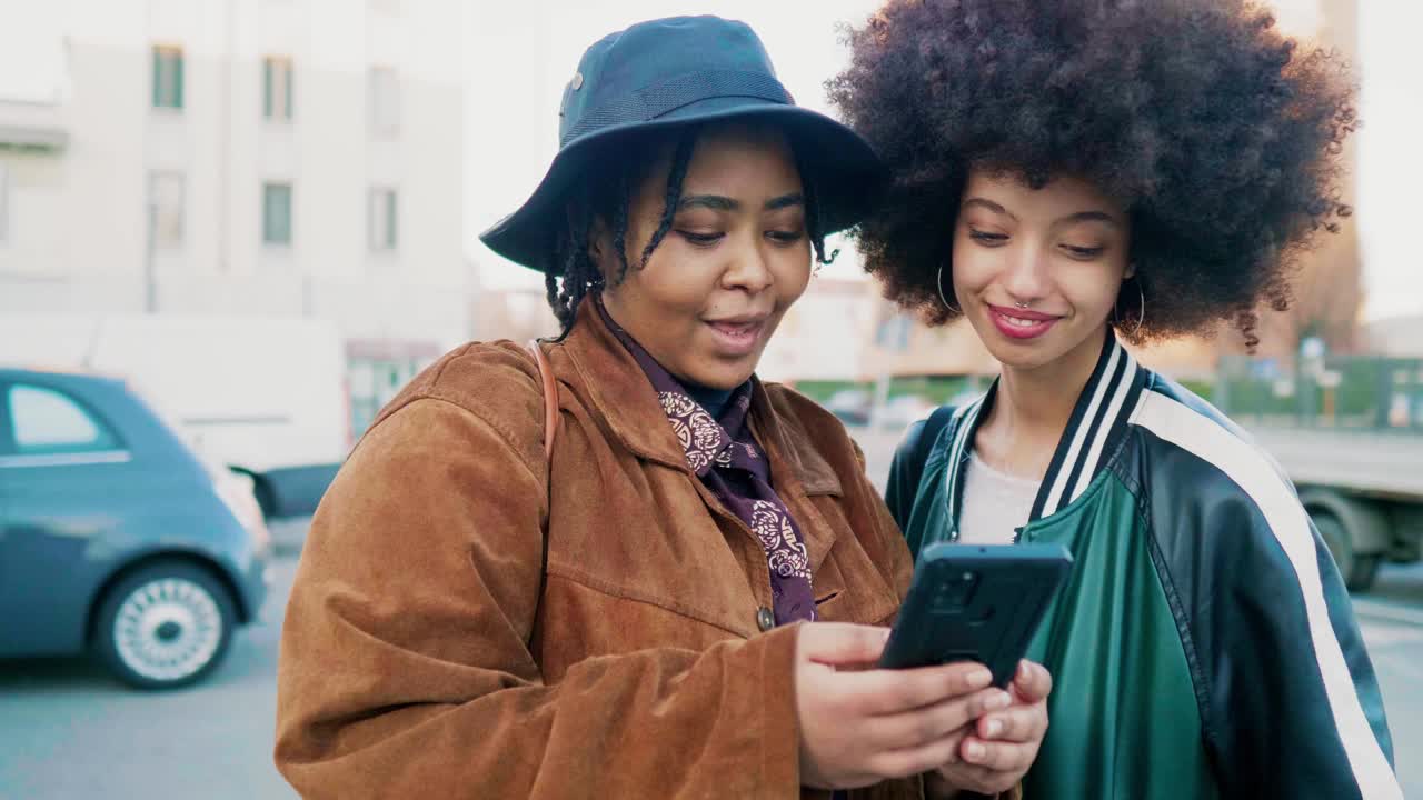 两个女人站在街上看智能手机上的信息视频素材