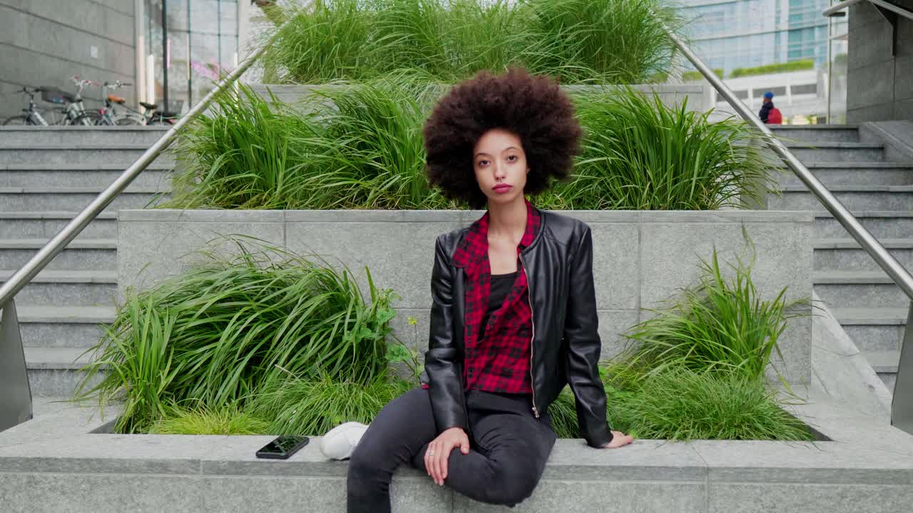 年轻女子坐在台阶上与绿色的草地在城市视频素材