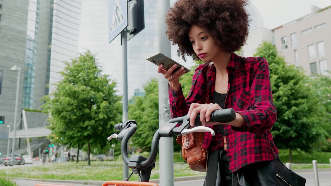 一名骑着城市自行车的女子微笑着看着智能手机视频下载