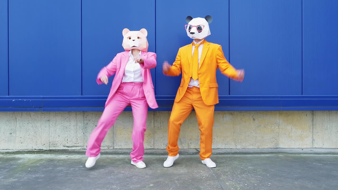 一对戴着动物面具的商业夫妇在蓝墙前跳舞视频素材