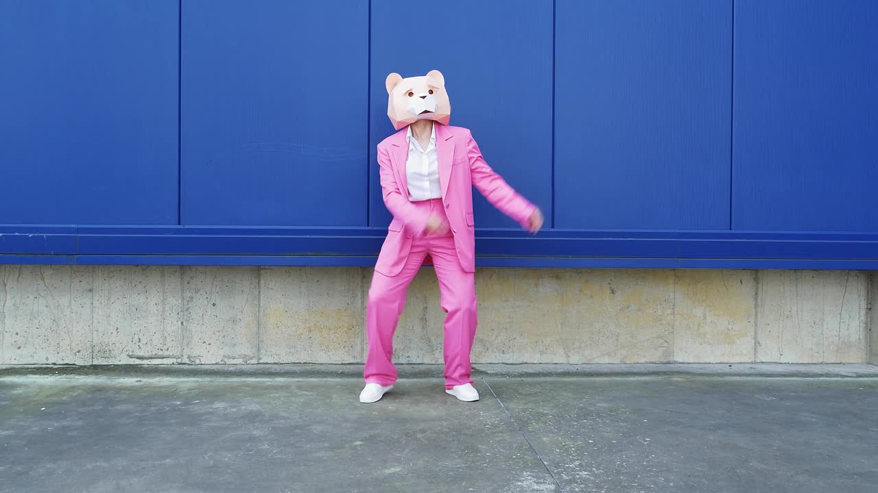 一个穿着粉色西装戴着熊面具的女人在墙前跳舞视频素材