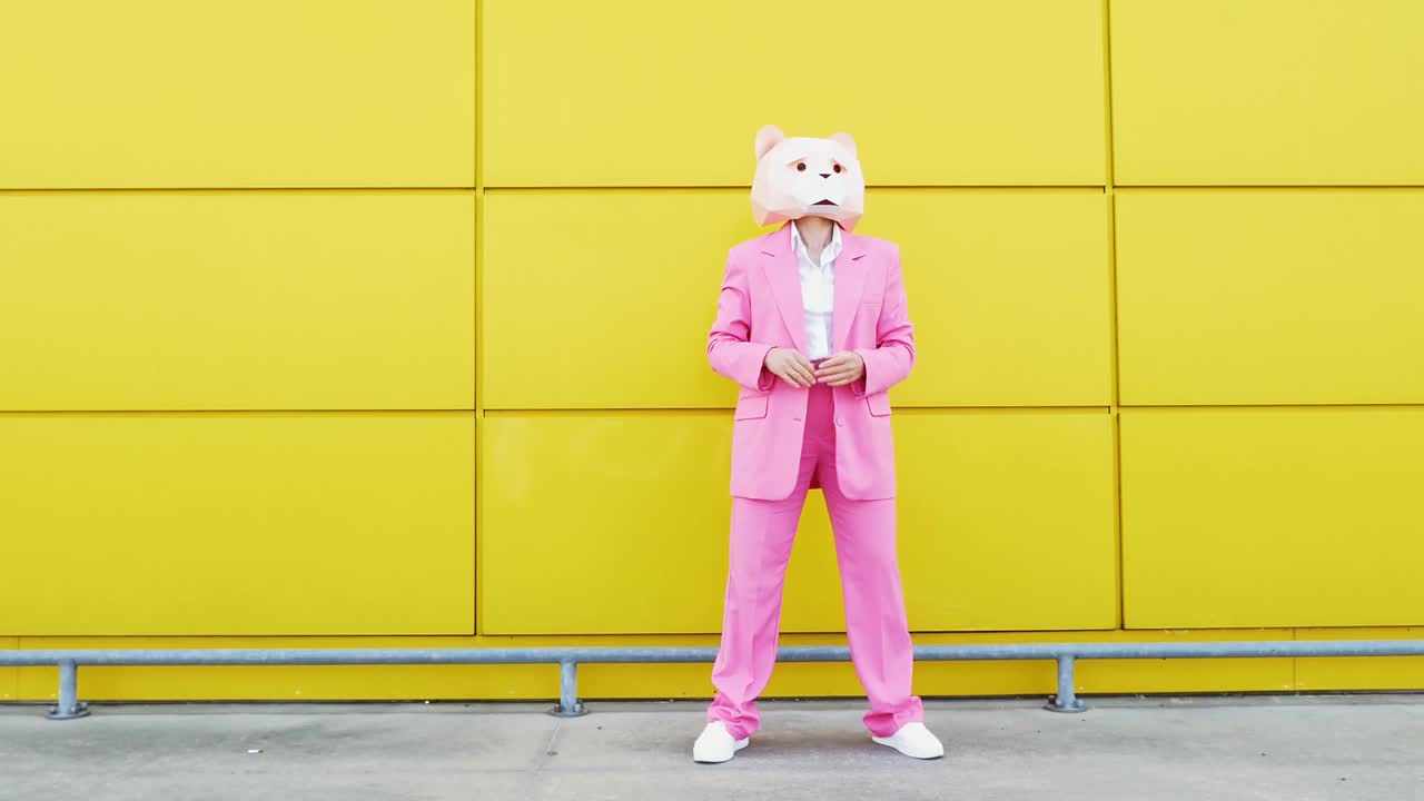 一个穿着粉色西装戴着熊面具的女人在墙前跳舞视频下载