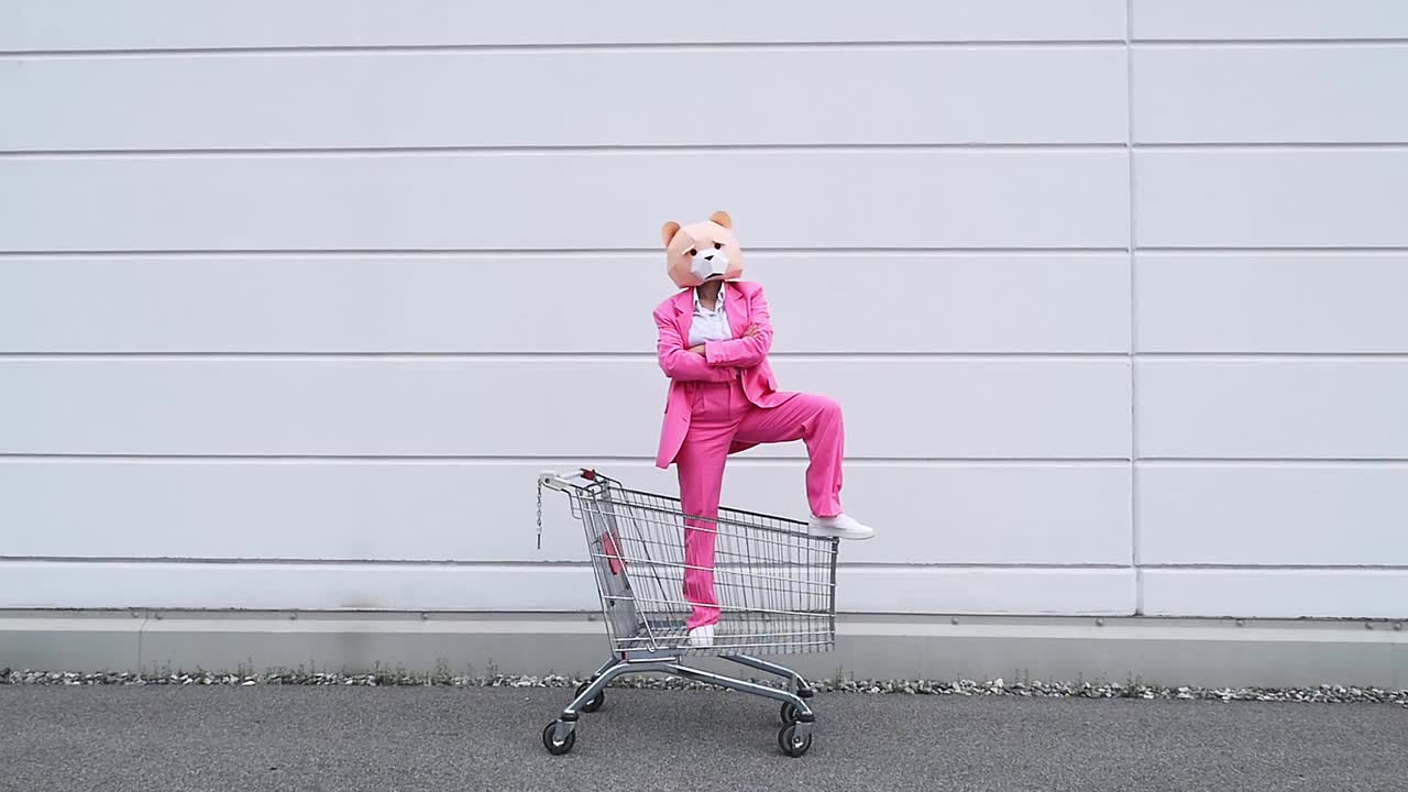 戴着熊面具的女人站在购物车里跳舞视频素材