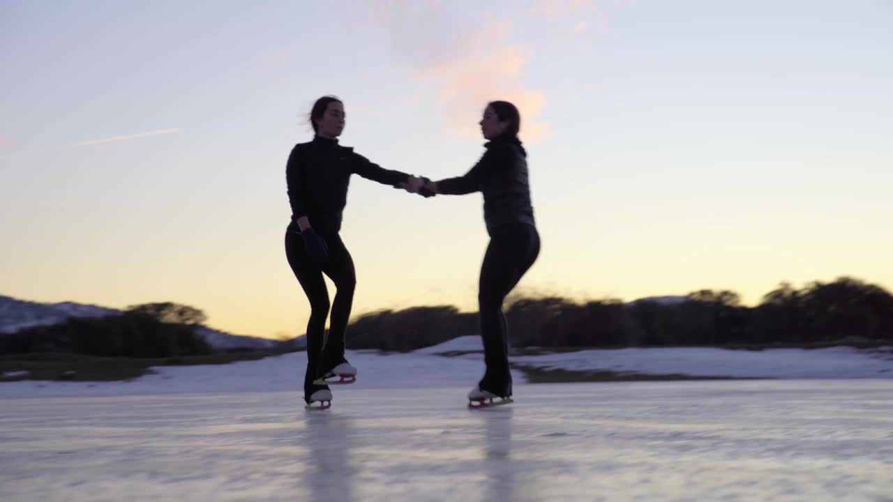 日落时分，两个女人在冰冻的湖面上表演死亡螺旋视频下载