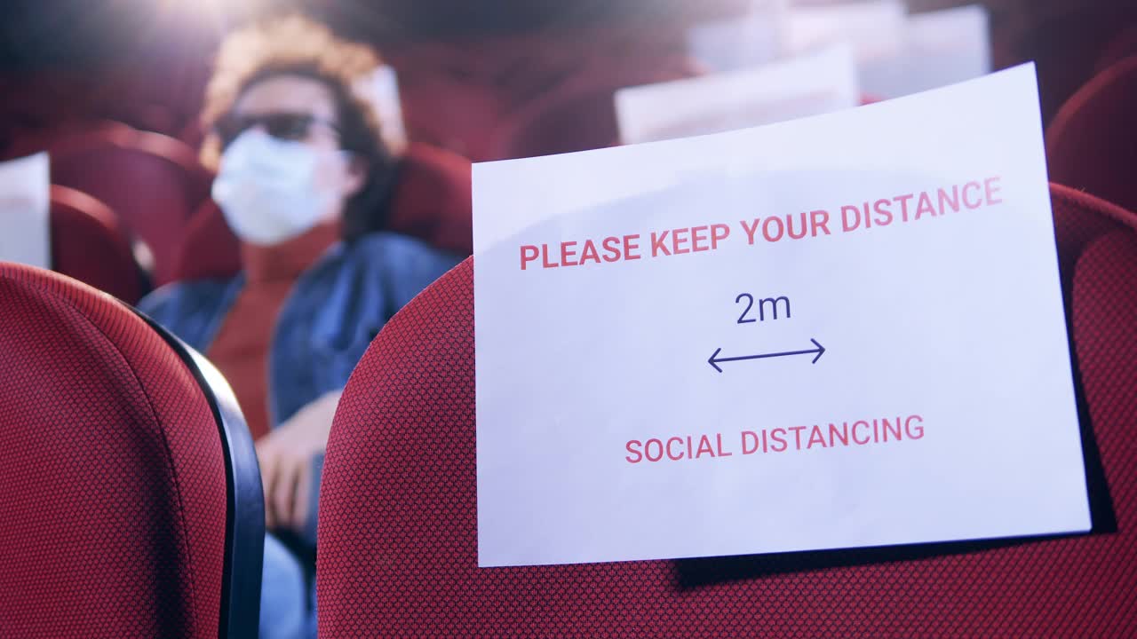 电影院里有个男人，座位上有保持社交距离的标志视频下载