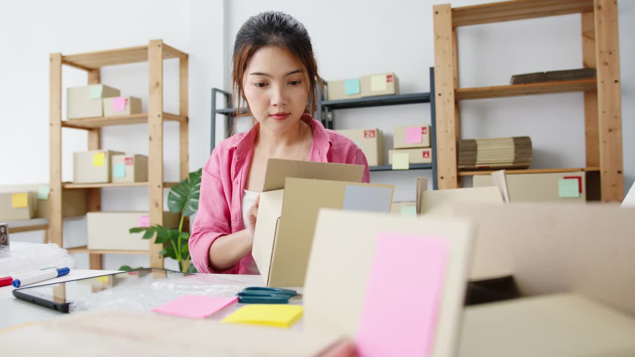 年轻的亚洲企业家女商人检查产品采购订单库存和保存到平板电脑工作在家里的办公室。视频素材