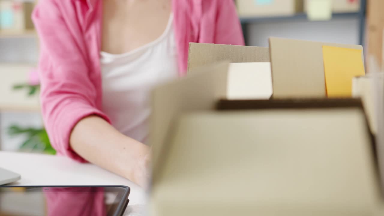 年轻的亚洲企业家女商人检查产品采购订单上的库存，并保存到电脑笔记本电脑工作在家里的办公室。视频素材