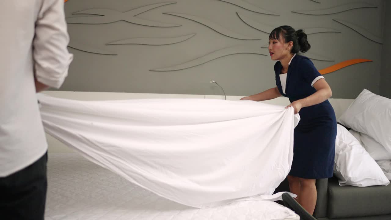 酒店的管家在整理床铺把床单铺在床上视频素材