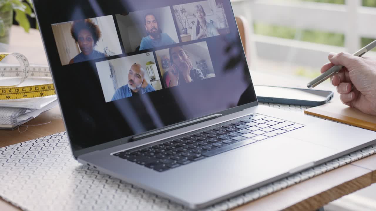 女企业主在笔记本电脑前做笔记，显示虚拟团队会议视频素材