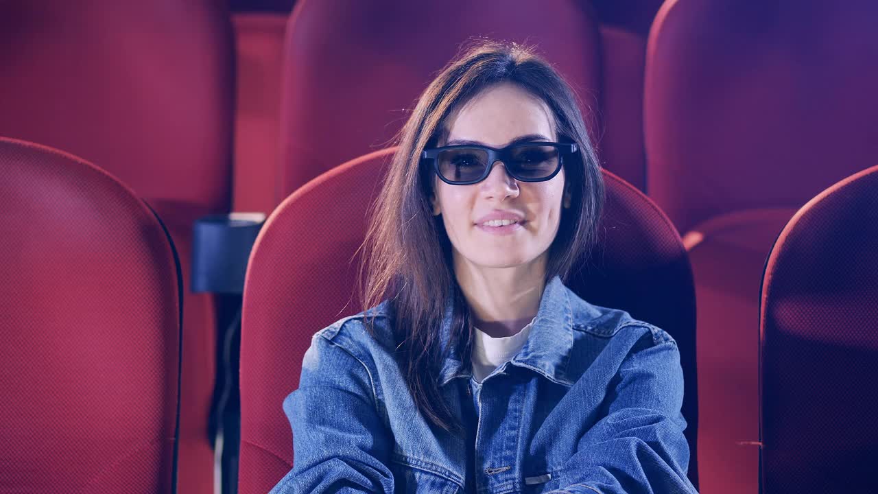 一个戴眼镜的女人在看电影时面带微笑视频素材