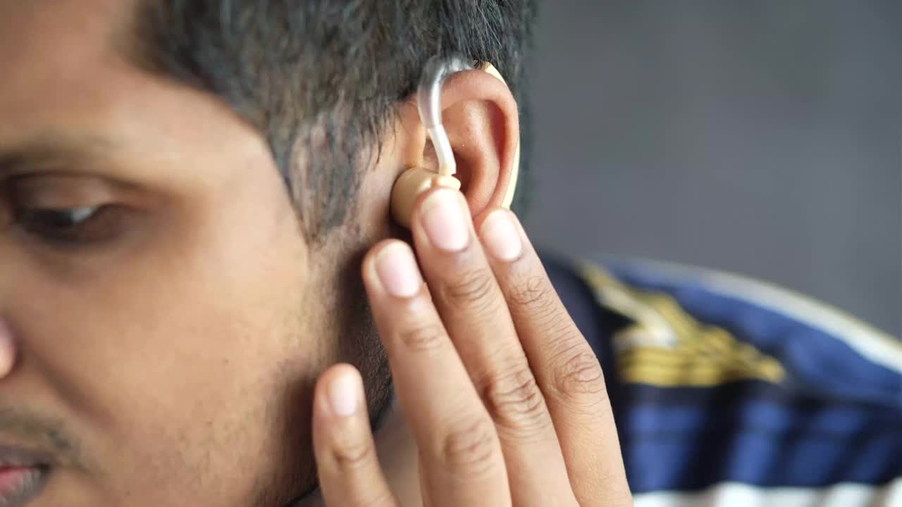 助听器概念，一个有听力问题的年轻人。视频下载
