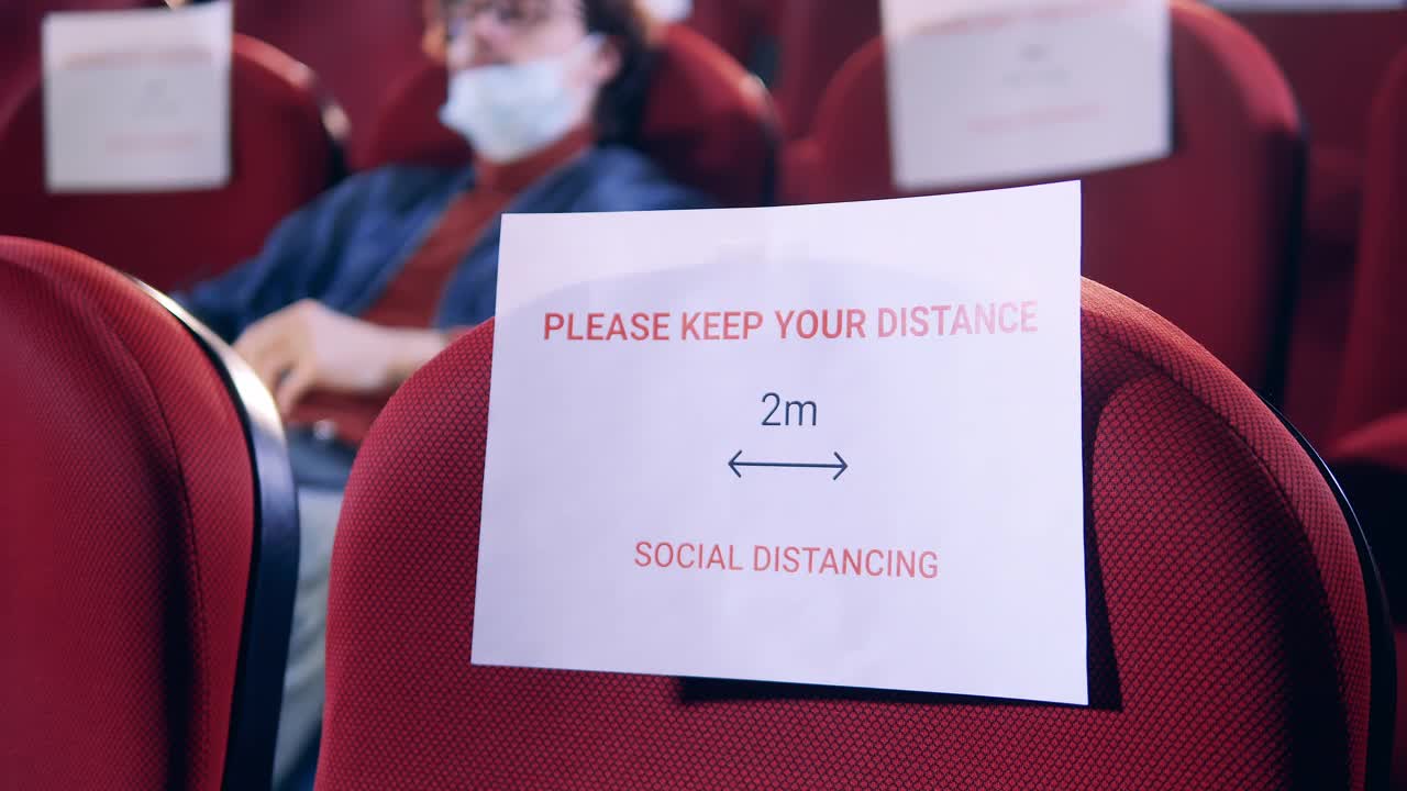 电影大厅里有一个男人，这是保持社交距离的标志视频下载