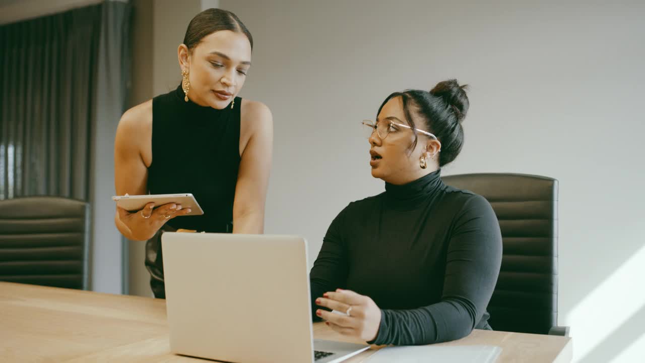 两名女商人在办公室用笔记本电脑讨论的4k视频片段视频素材