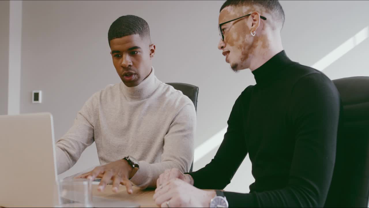 两名商人在办公室用笔记本电脑讨论的4k视频片段视频素材