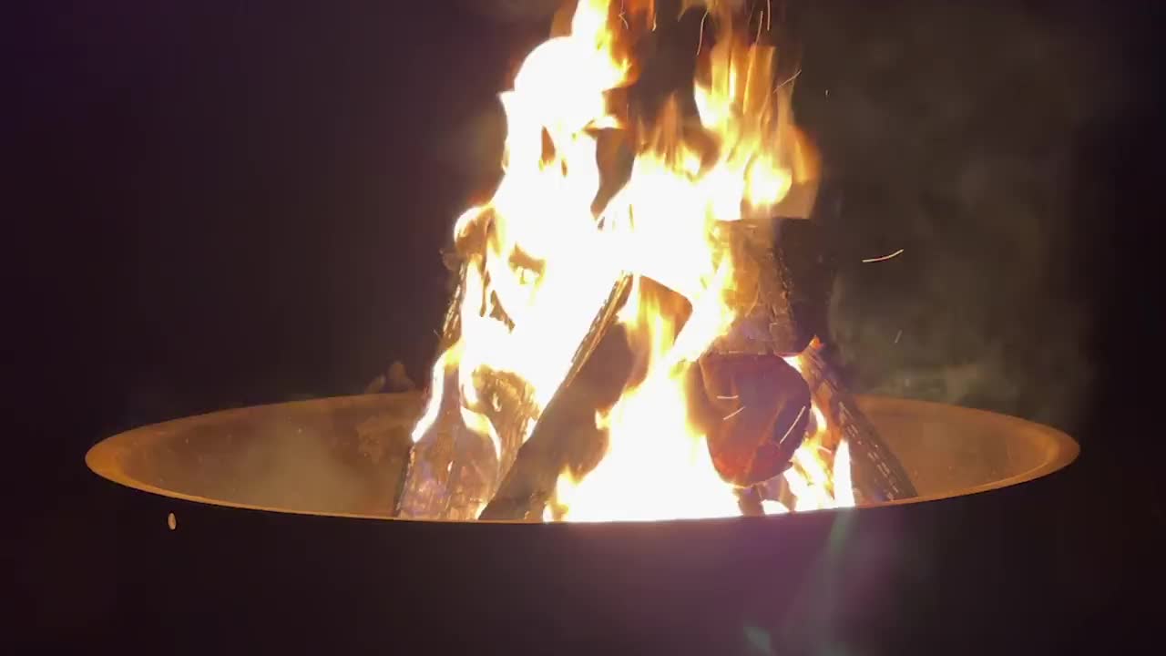 在火坑里燃烧原木，在篝火旁度过舒适的露营之夜视频下载