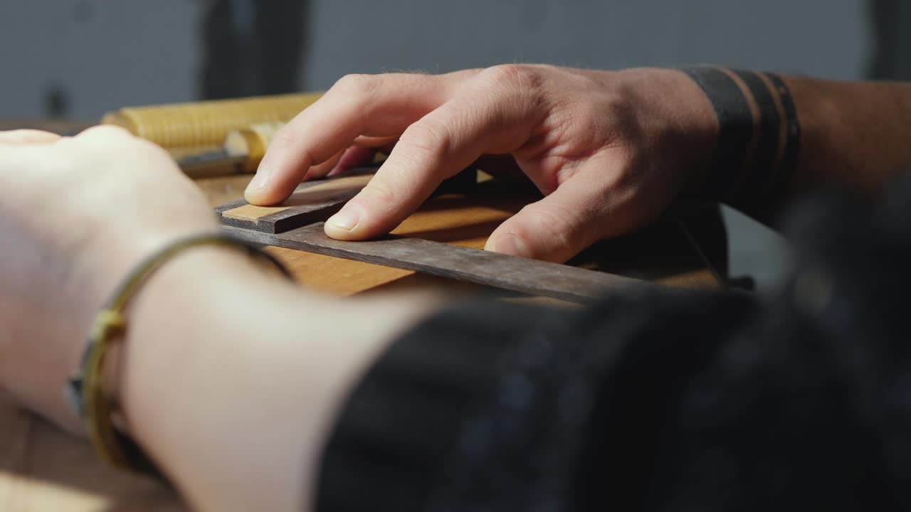 木匠将一块木板放在工作台上，用铅笔在木板上画线。视频素材