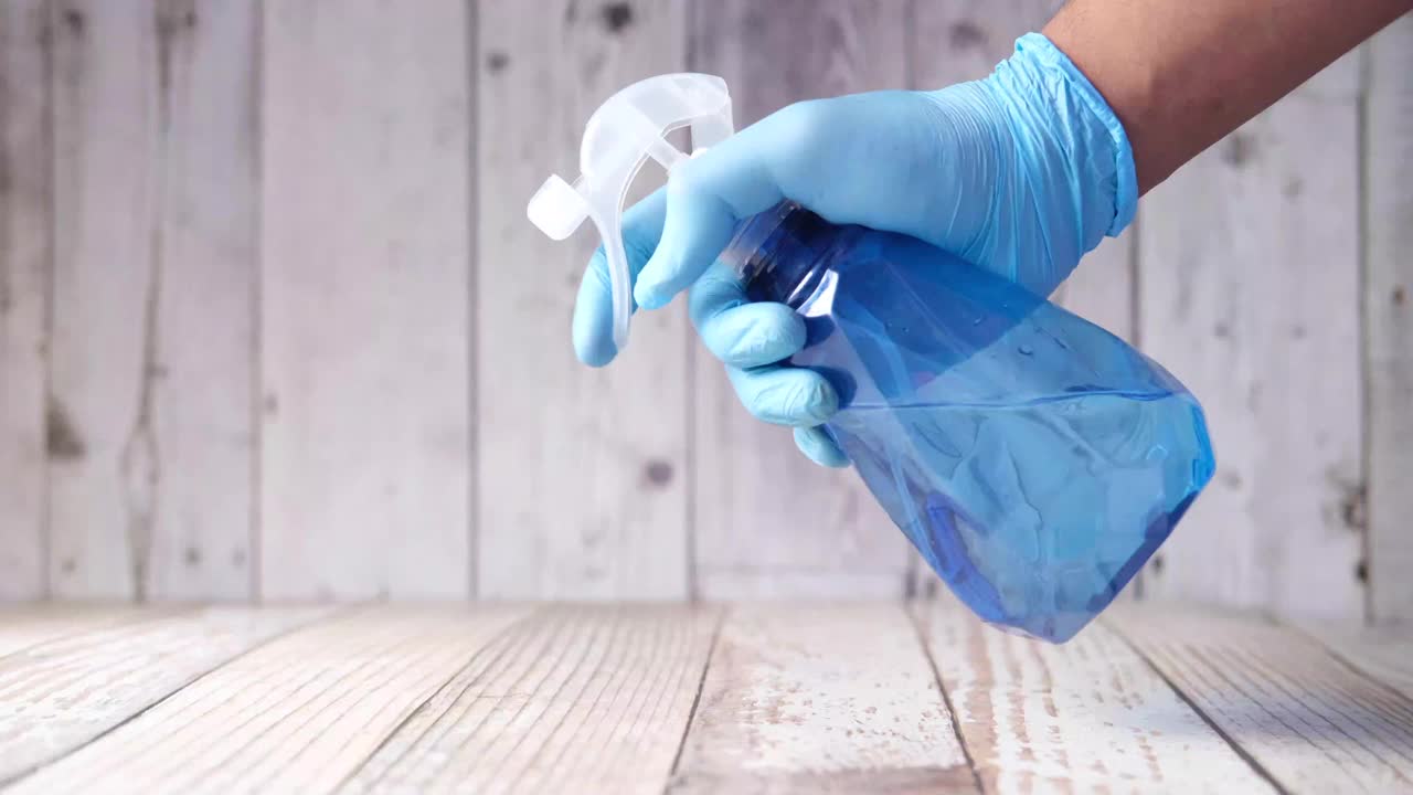 手戴蓝色橡胶手套，手持喷瓶清洗台面视频下载