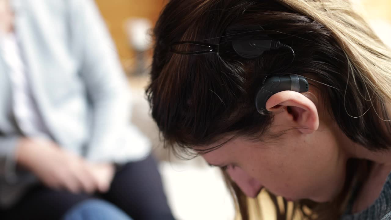 一位戴着人工耳蜗的年轻女子正在与一位心理学家交谈视频素材