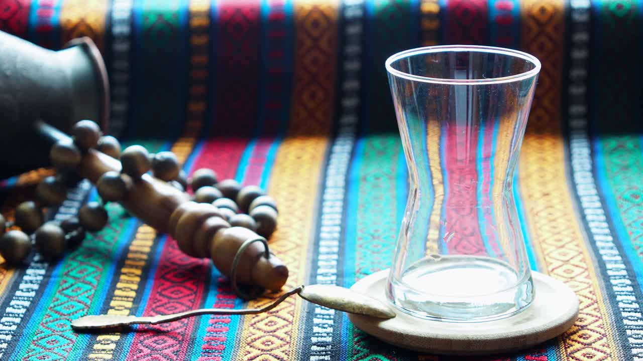 传统的土耳其茶倒入玻璃杯中。桌上放着一杯热腾腾的红茶，还有彩色的桌布。土耳其,伊斯坦布尔视频素材