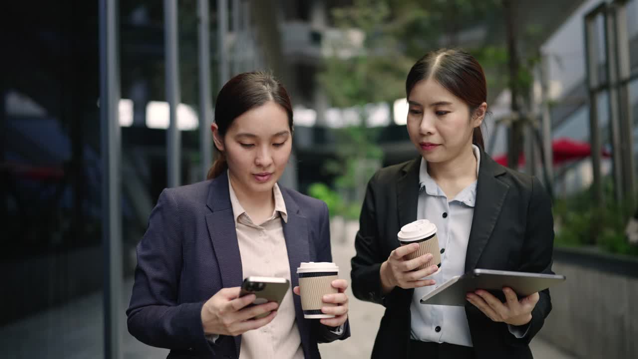 两位女商人边走边用数码平板电脑视频素材