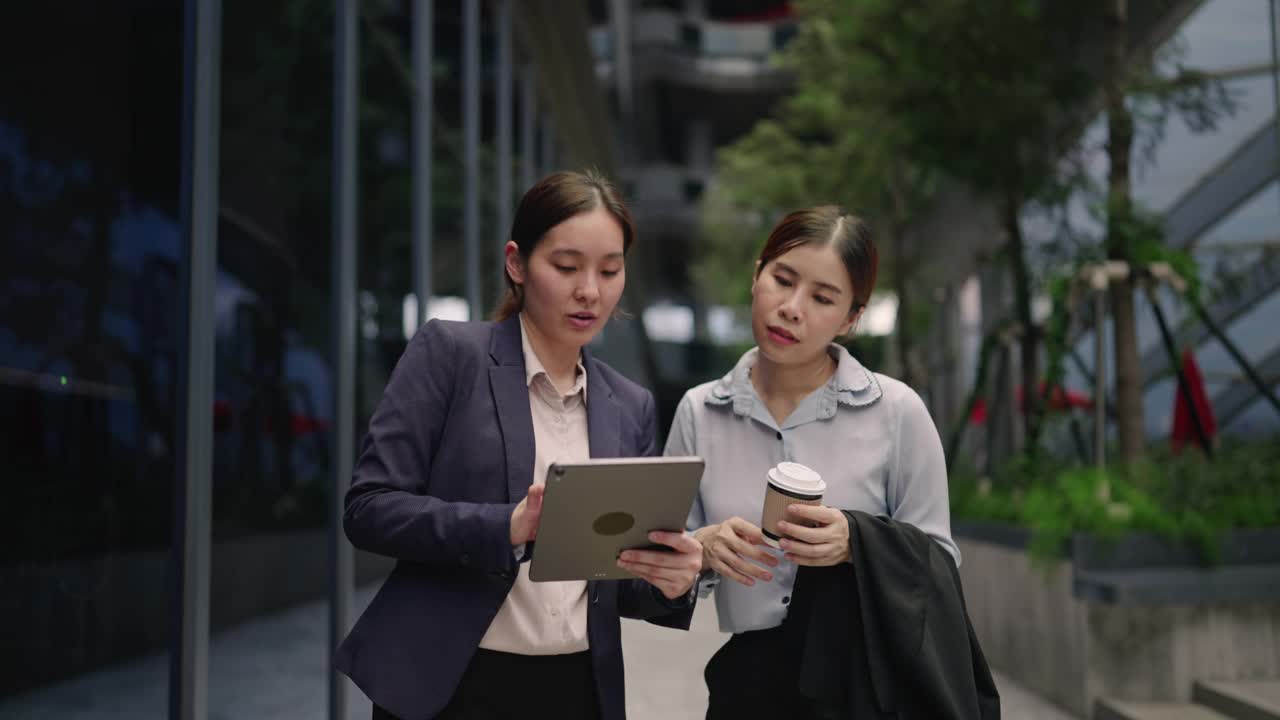 两位女商人边走边用数码平板电脑视频素材