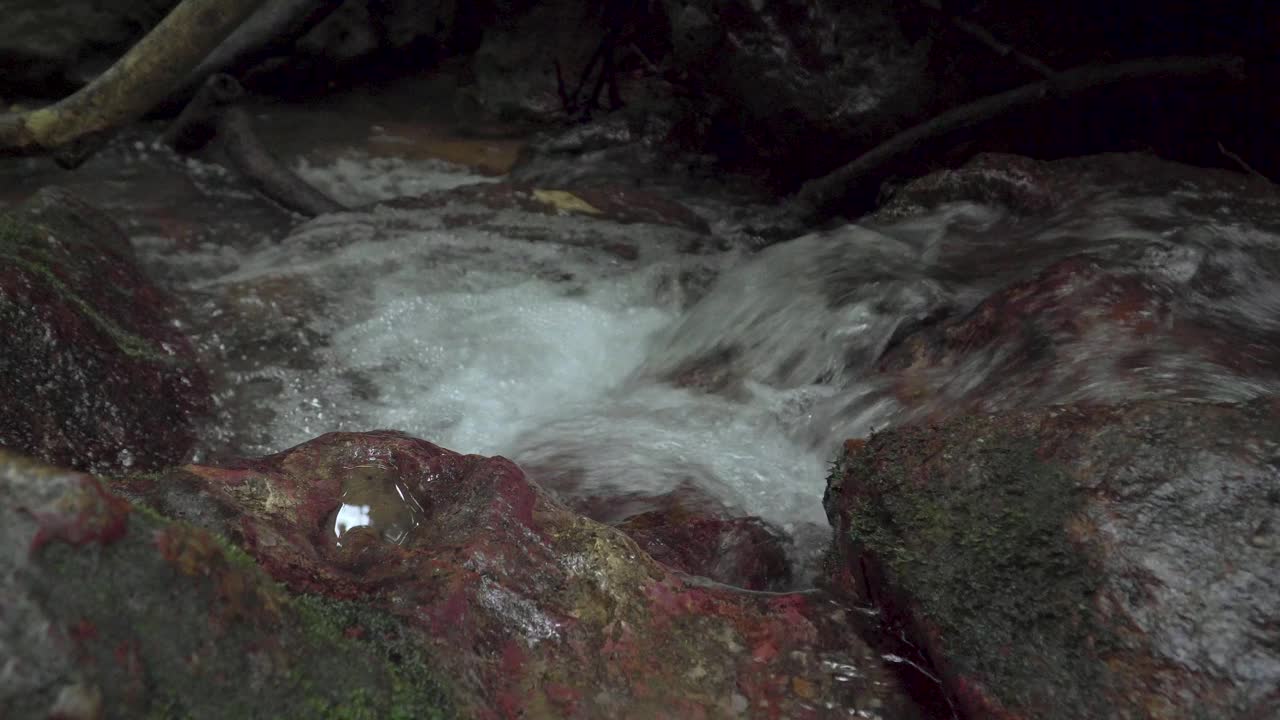 在热带雨林中，清澈的溪水流经长满苔藓的岩石、巨石和砾石之间的石溪。湍急的瀑布河急速溅起水花。视频素材