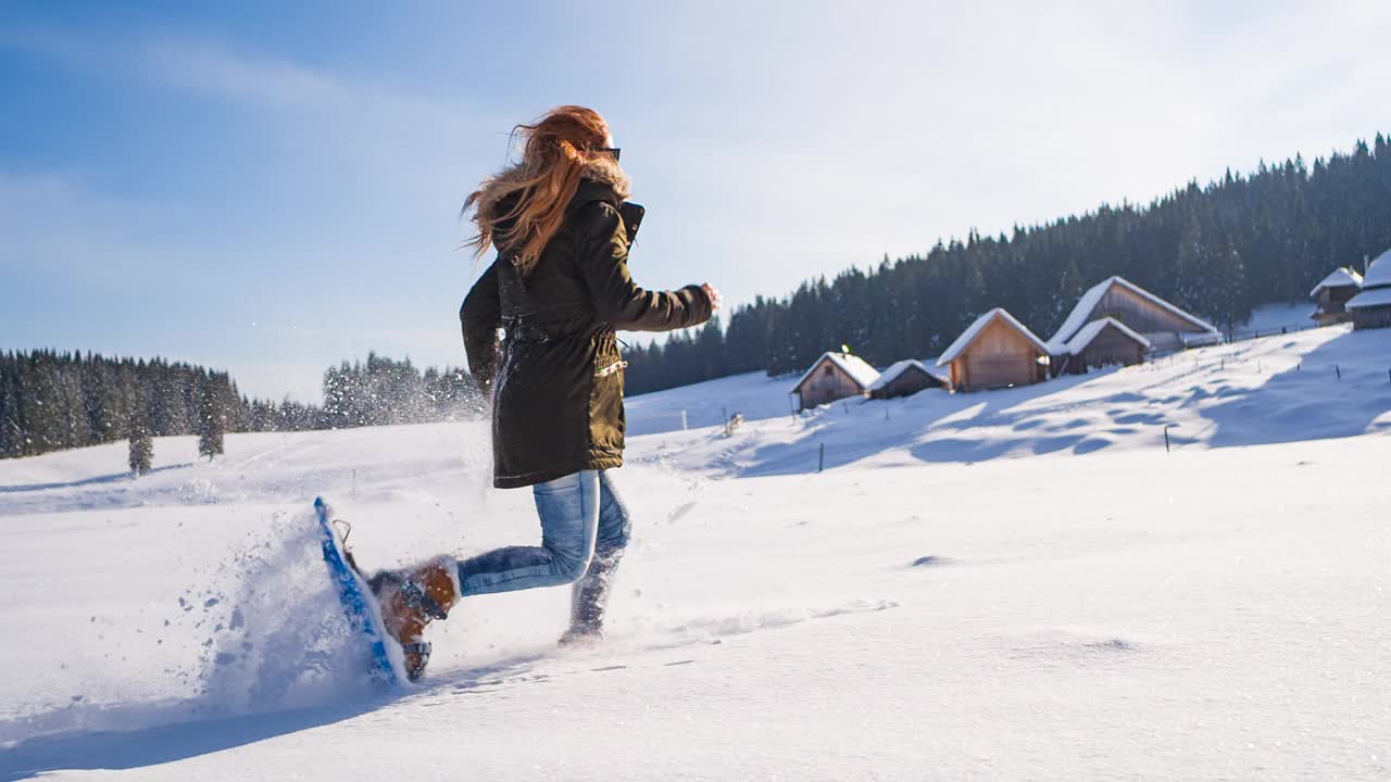 脚上系着雪鞋，在刚落下的粉雪上奔跑，背景风景如画视频下载