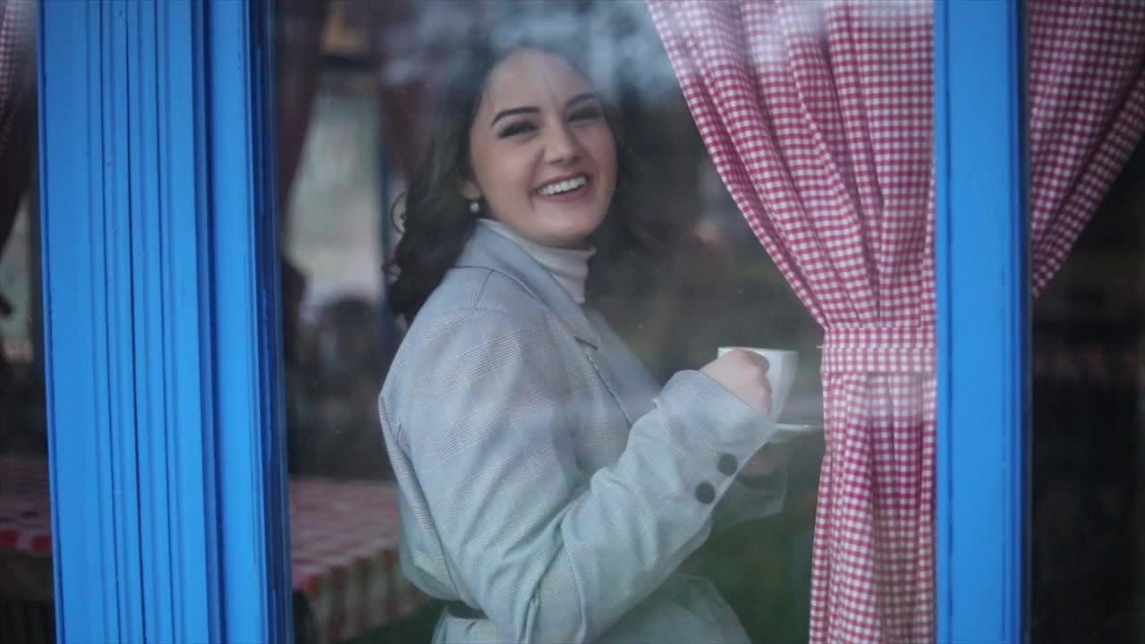 一位美丽、优雅、复古的年轻女子站在餐厅的窗边。视频下载