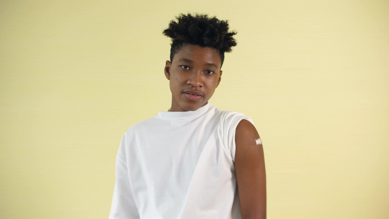 一名非洲裔美国青少年在接种疫苗后竖起大拇指，并展示手臂上的绷带视频下载