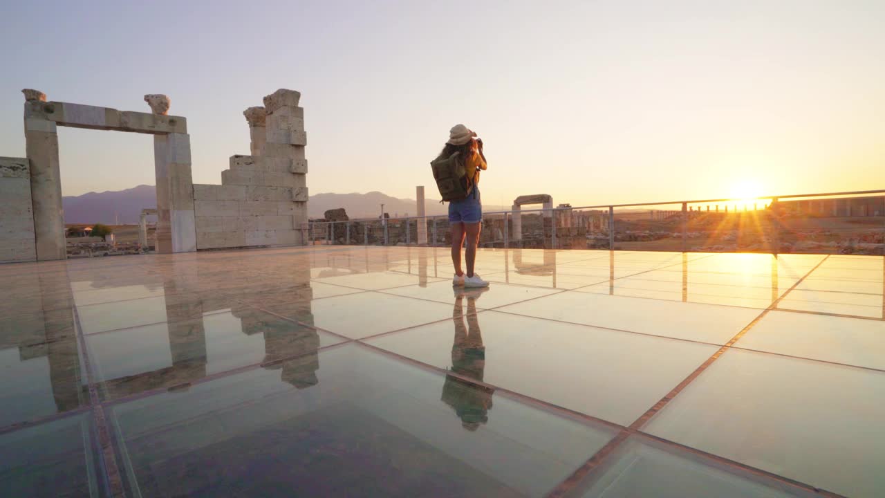 旅行者旅行者摄影师女孩在黄昏时在莱库斯的老底嘉古城遗址拍照视频素材