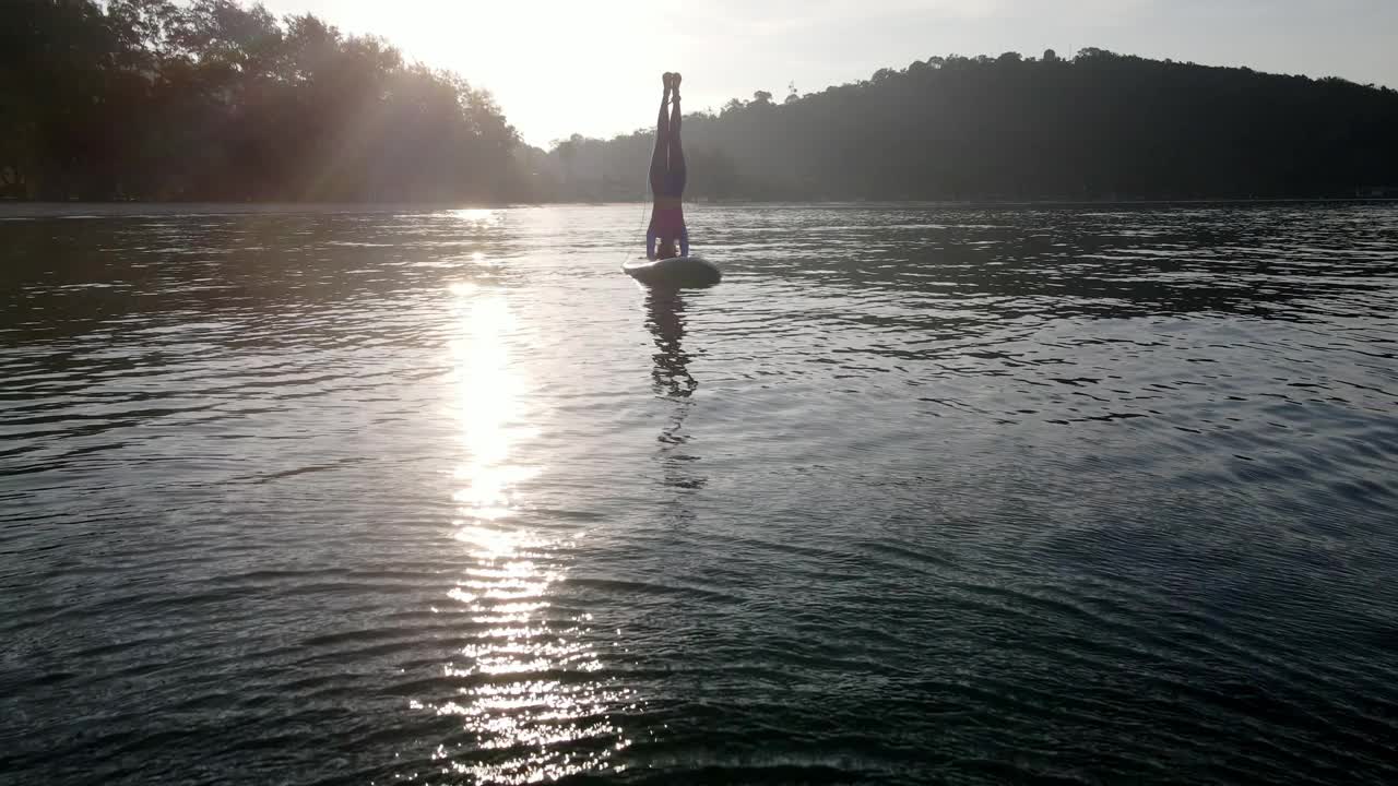 在阳光明媚的夏天，活跃的女性瑜伽练习在海洋上站立桨板。视频下载