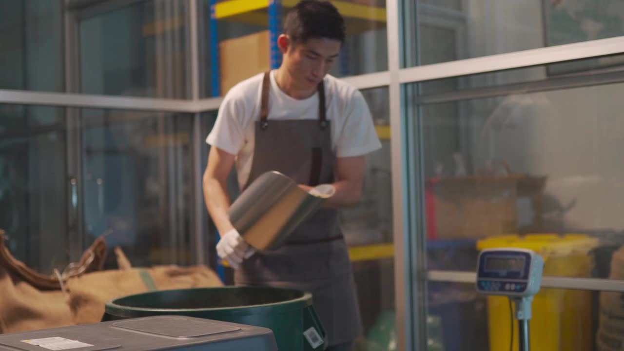 亚洲华人工匠将生咖啡豆从桶中舀到秤机上，并将其混合在工厂仓库的咖啡烘焙过程中视频下载