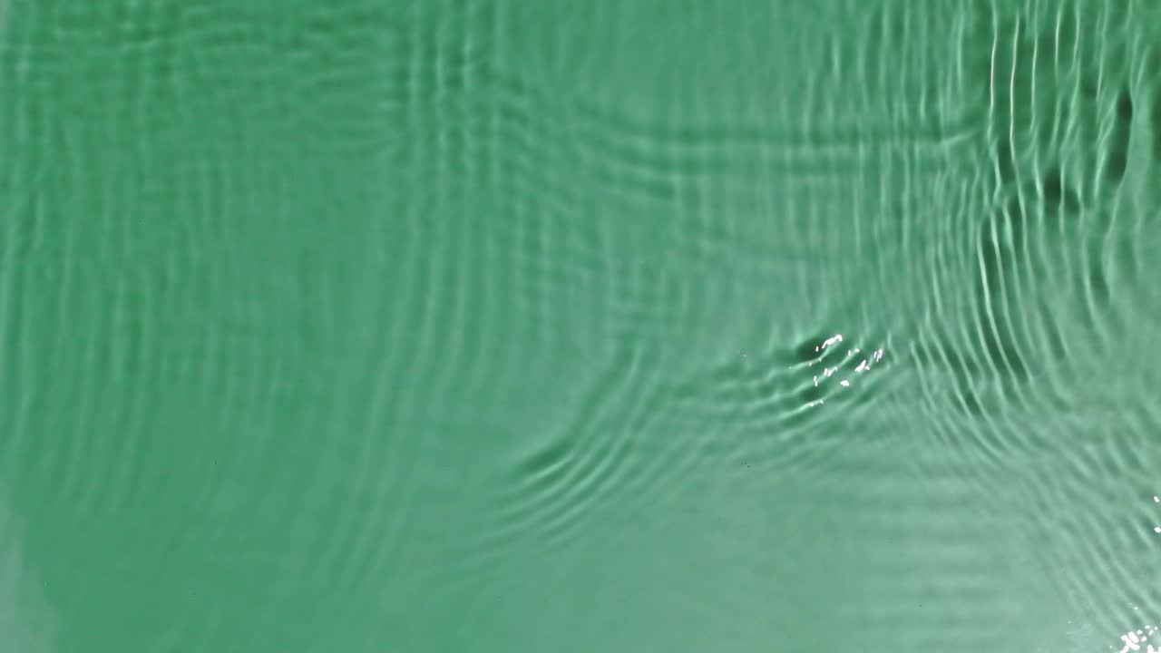 绿色的水纹理与涟漪，在阳光下透明。背景为化妆品或水疗概念背景。本空间视频素材
