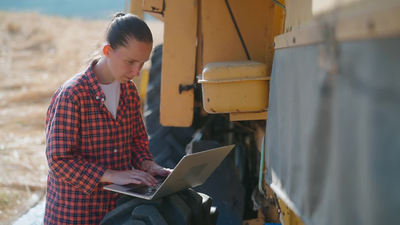 女农民使用笔记本电脑旁边的联合收割机视频素材