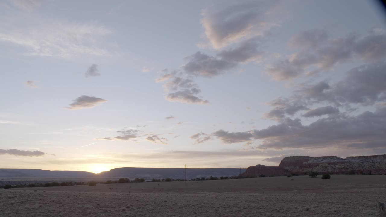 当太阳在bg落下时，沙漠景观的广角。蓝天白云可见。可见的山脉、高原或台地美国西南部，可能是亚利桑那州。视频下载