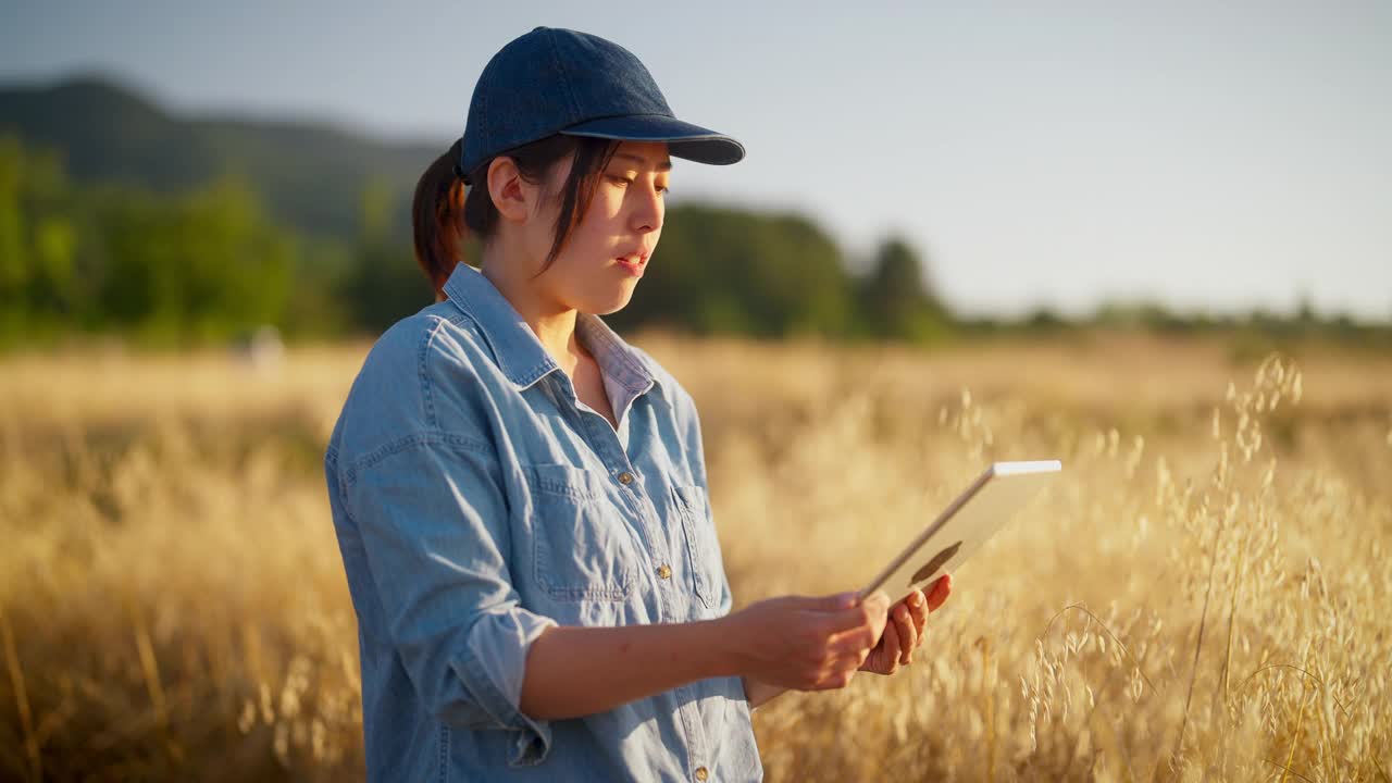 年轻的女农民在农田里拿着数字平板电脑视频下载