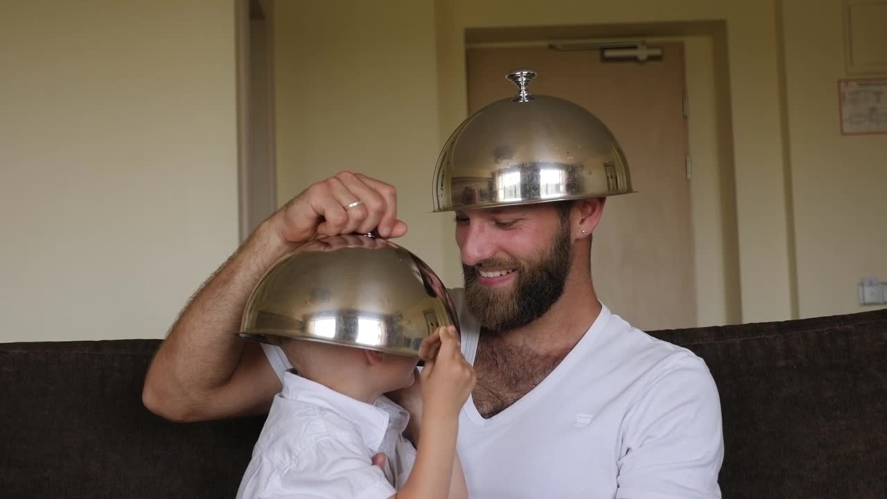 一位父亲和他的儿子在酒店里玩着盘子的盖子。视频下载