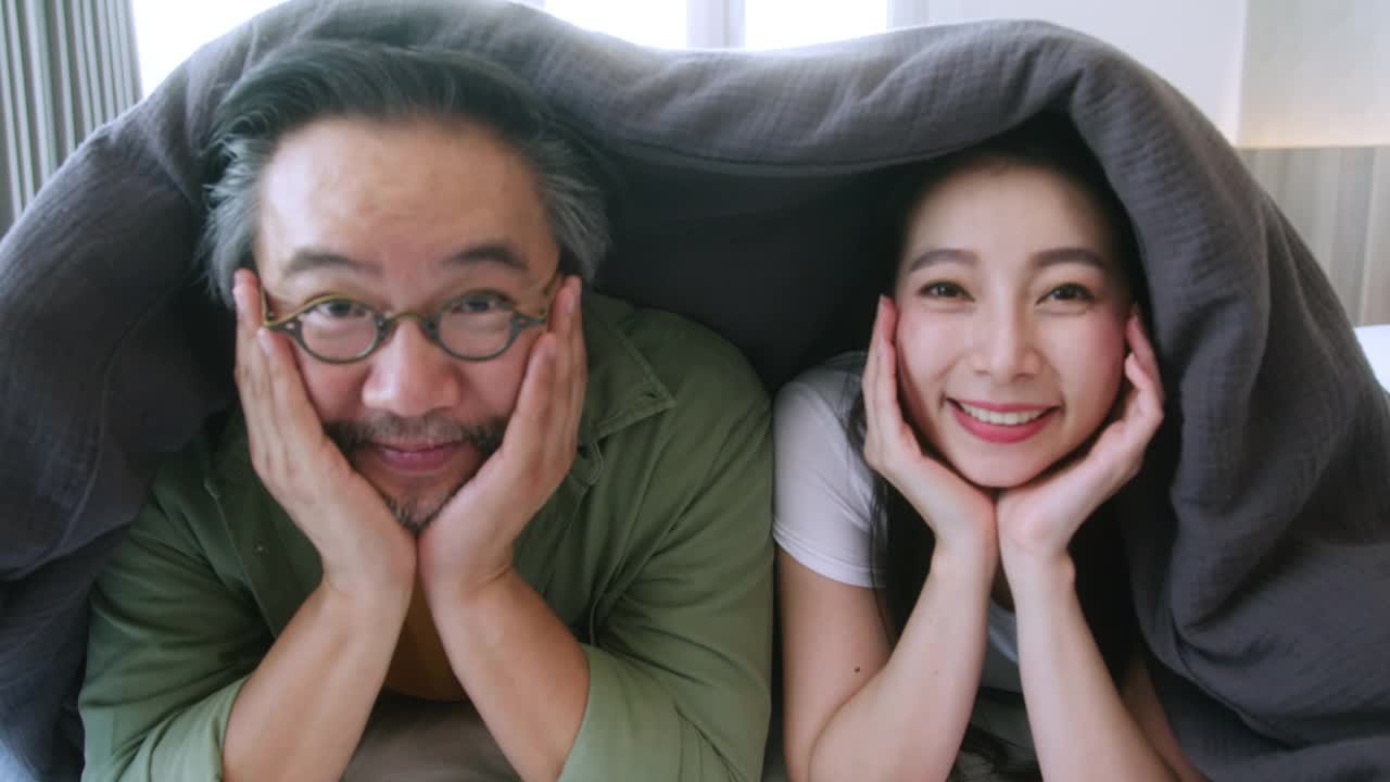 幸福亚洲结婚夫妇手牵脸一起动，幸福快乐一起在床上盖毯子，幸福家庭概念视频素材