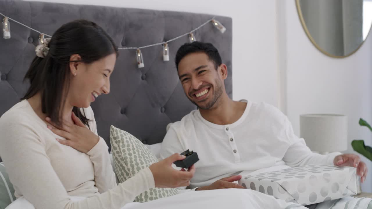 一段4k视频记录了一对年轻夫妇在家床上交换礼物视频素材
